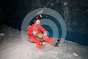 A mountaineer caver eats in a deep ice cave