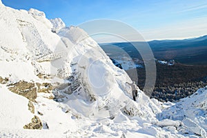 The mountaineer climbing the mountain top covered with ice and snow, man hiker going at the peak of rock. Winter season.