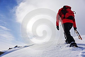 Mountaineer climbing a snowy peak in winter season.