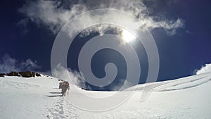 Mountaineer climbs snowfield on a sunny day