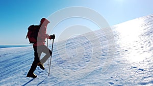 Mountaineer climbs a snowy mountain over blue clear sky. Winter