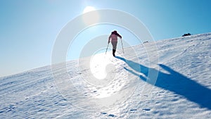 Mountaineer climbs a snowy mountain over blue clear sky. Winter