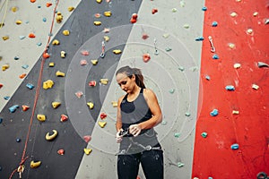 Mountaineer fitting harness preparing for ascent on indoor rock