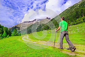 Mountaineer in a green t-shirt with poles, Austria