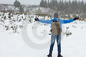 Mountaineer man with blue jacket and backpack enjoying snow with open arms on top of a mountain.Copy space