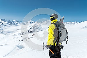 A mountaineer man holds an ice ax high in the mountains covered with snow. View from the back. outdoor extreme outdoor