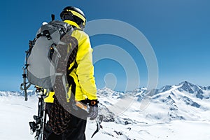 A mountaineer man holds an ice ax high in the mountains covered with snow. View from the back. outdoor extreme outdoor