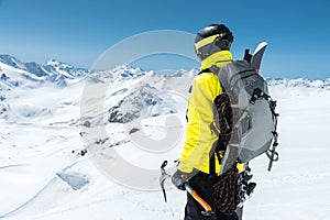 A mountaineer man holds an ice ax high in the mountains covered with snow. View from the back. outdoor extreme outdoor