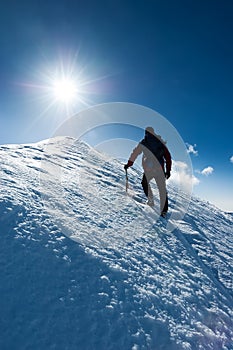 Mountaineer reaches the summit of a snowy peak. Concept: courage