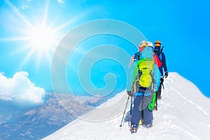 Mountaineer reaches the top of a snowy mountain in a sunny winter day