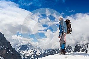 Mountaineer reaches the top of a snowy mountain in a sunny winter day photo