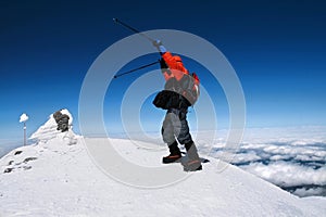 Mountaineer reaches the top of a snowy mountain in a sunny winter day. Travel sport lifestyle concept