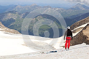 Mountaineer standing on glacier and looking towards Grossglockner High Alpine Road and mountain panorama in Austria