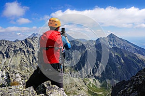 Mountaineer taking picture with smartphone in the mountains