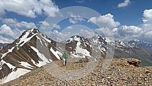 Mountaineer - a traveler with trekking poles walks along the mountain torus.