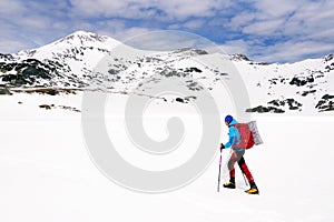 Mountaineer traversing an iced lake in Retezat Mountains..