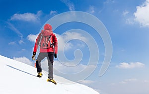 Mountaineer walking uphill along a snowy slope.