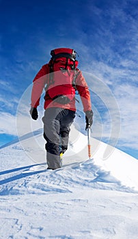 Mountaineer walks on the summit of a snowy peak. Concepts: deter