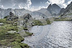 Mountaineering by the mountain lake among rocky peaks and clouds