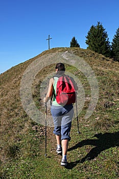 Mountaineering woman walking towards mountain cross