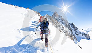 Mountaineers climb a snowy peak. In background the famous peak Dent du Geant in the Mont Blanc Massif, the highest european mounta photo