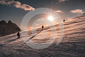 Mountaineers climbing in blizzard on snowy hill at sunset