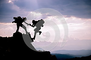 Silhouette of helping hand between two climber.Adventurous people;Hikers climbing on mountain. Help, risk, support, assistance