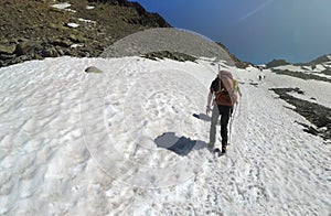 Mountaineers walking up along a snowy ridge with the skis in the backpack