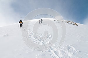 Mountaineers walking up along a snowy ridge with the skis in the backpack. Skier on the climbing track for freeride