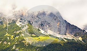 Mountains in the alps with cloudy hillsides, alp and chalet photo