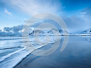 Mountains, beach and wave. Skagsanden beach, Lofoten islands, Norway. Winter landscape near the ocean.