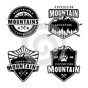 Mountains camping and outdoor adventure set of four monochrome vector emblems, labels, badges or logos isolated on white