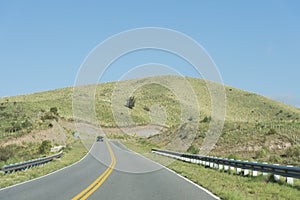 Mountains of Cordoba, Argentina: road, a car, grassy hill and cloudless sky