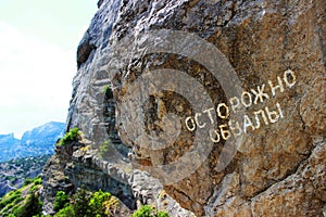 Mountains covered with grass and forest. Summer, the republic of Crimea. Inscription on the mountain in russian: cautiously, crash