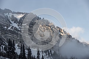 the mountains are covered in snow and mist on a cloudy day