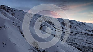 Mountains covered with white snow against a sunset sky with beautiful flowers. Beautiful landscape shot from the air on