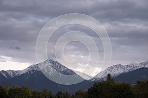 Mountains cowered with snow and cloudy sky background.