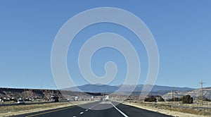 Mountains in the Distance as a Desert Highway Passes Through a Red Rock Valley on a Clear Fall Day