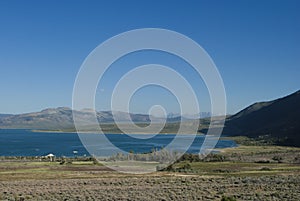 Mountains road trip. Mono Lake and mountains in the distance, blue sky and asphalt road in yearly morning