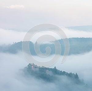 Mountains in fog at beautiful morning in autumn. Landscape with mountain valley, low clouds, forest, colorful sky , nature.