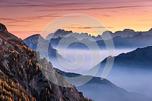 Mountains in fog at beautiful sunset in autumn. Dolomites, Italy