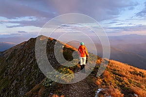 Mountains in the foggy morning. Landscape with beautiful cloudy sky. Successful sporty girl is standing at the path. The lawn with