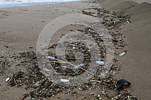 Mountains of garbage, old plastic bottles after a storm, the surf wave throws it on the sea sand of the city beach. Ecological