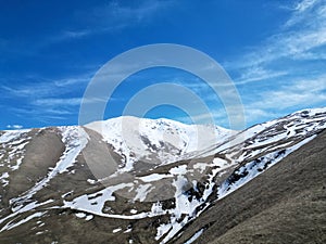 Mountains, grass, snowy cliff tops. sunny day, blue sky, clouds. Drone photo