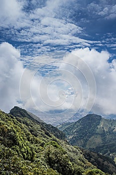 Mountains with grass and trees surrounding the capital of Costa Rica on a sunny day full of white clouds photo