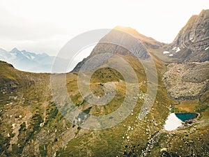 Mountains green lake with reflections and rocky shore in autumn time. Wild nature and rural mount valley. Fall grey weather rainy