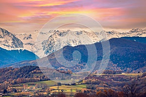 Mountains landscape in autumn. View of arable fields in the valley and mountain ridge covered with snow during sunset