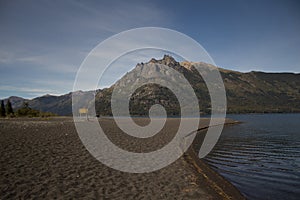 Mountains landscape with a lake on a dark sandy beach