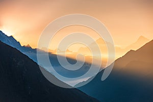 Mountains and low clouds at colorful sunrise in Nepal