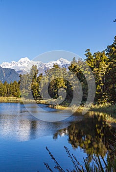 Mountains are reflected in the lake. Matheson lake, New Zealand